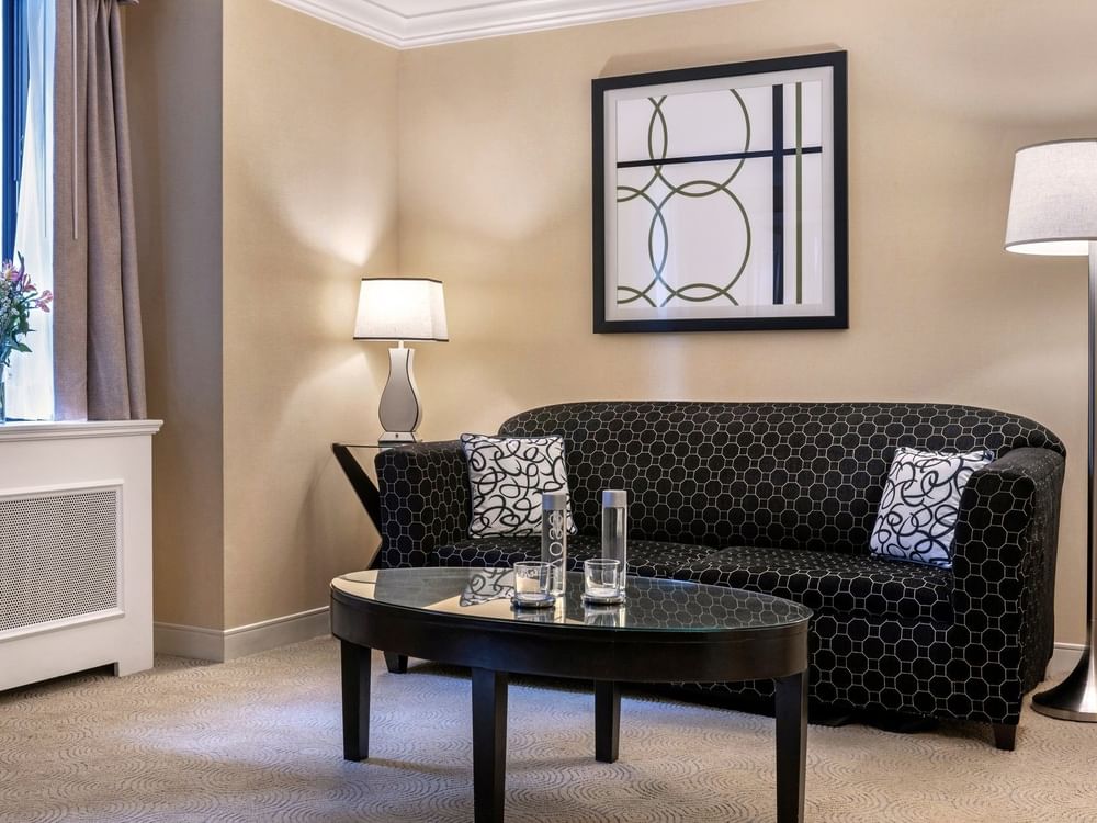 Black pattern sofa near floor lamp and hanging wall art in Premium Suite Two Queen Beds at Warwick Allerton Chicago