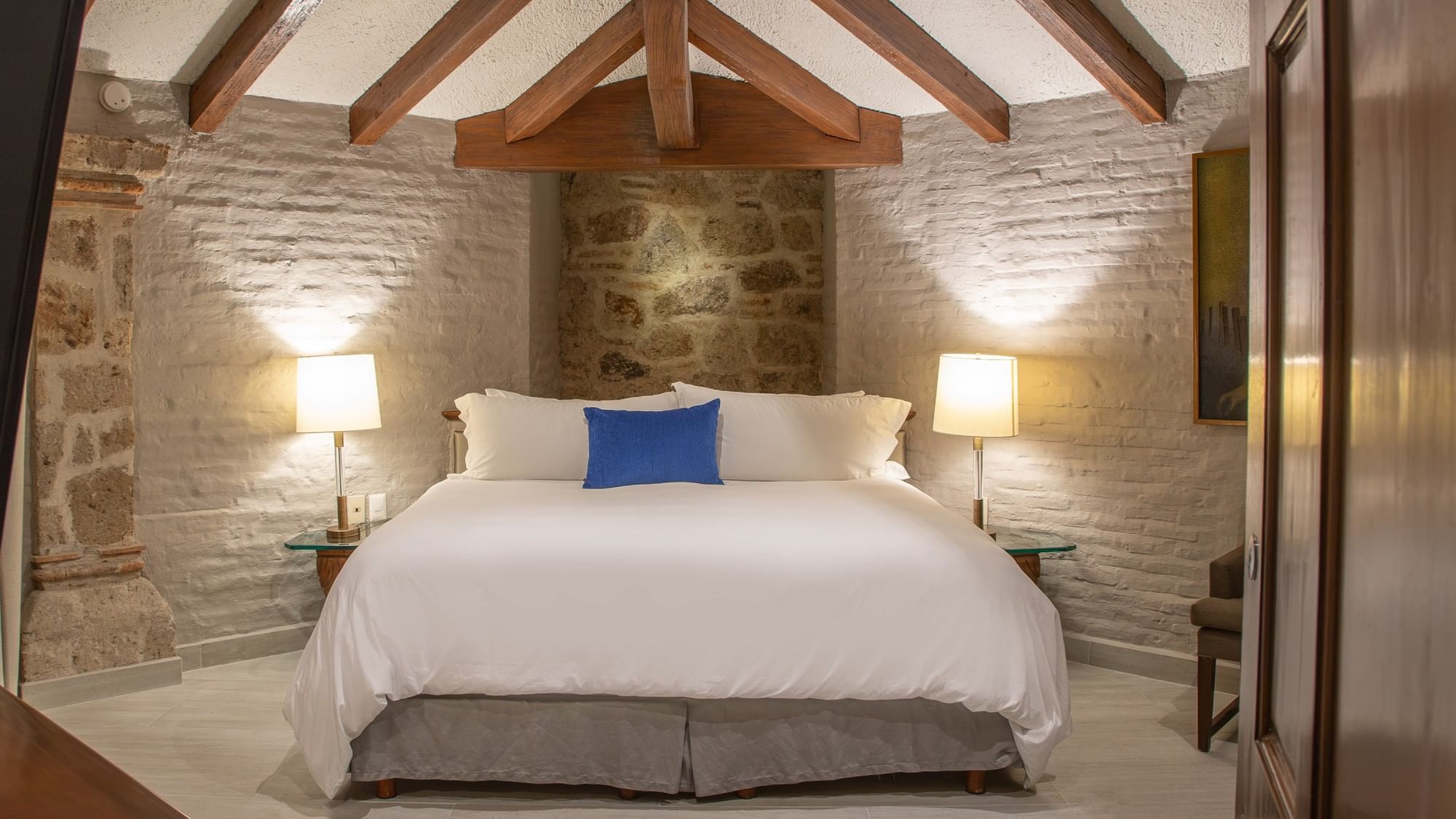 Suite Presidencial King con cama king, paredes de piedra, vigas de madera y lámparas en Quinta Real Guadalajara