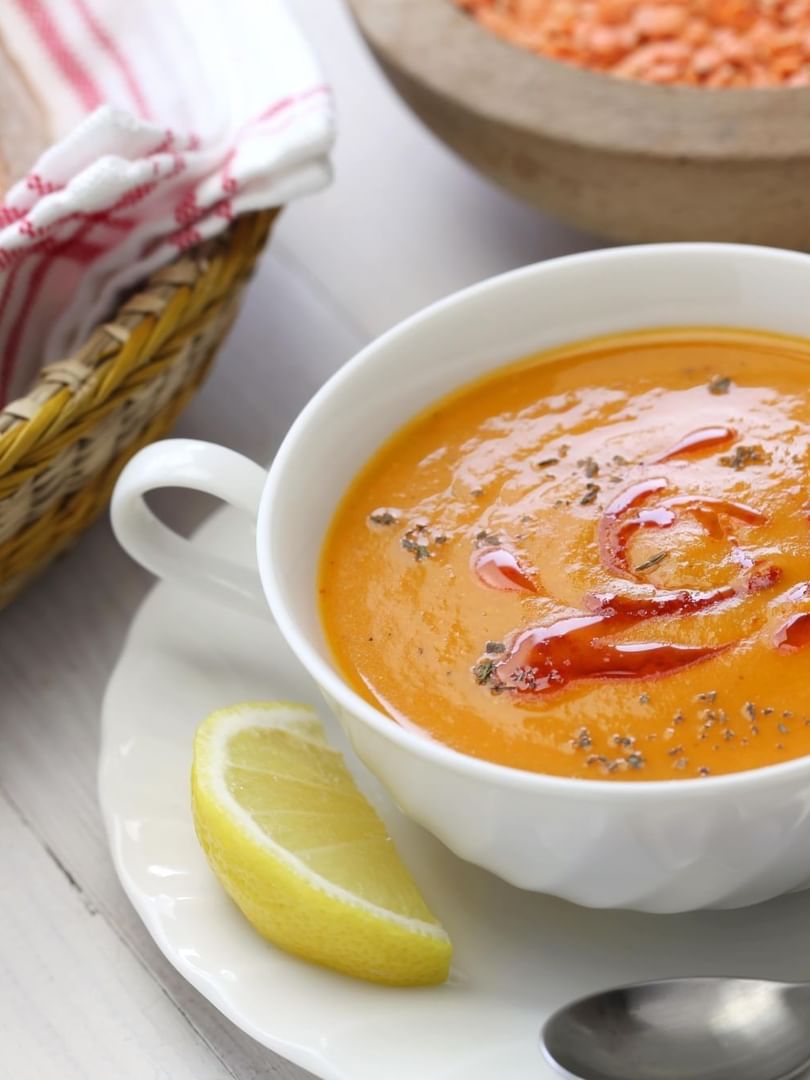 Orange soup with a lemon wedge under a basket of sliced bread at Warwick Ankara