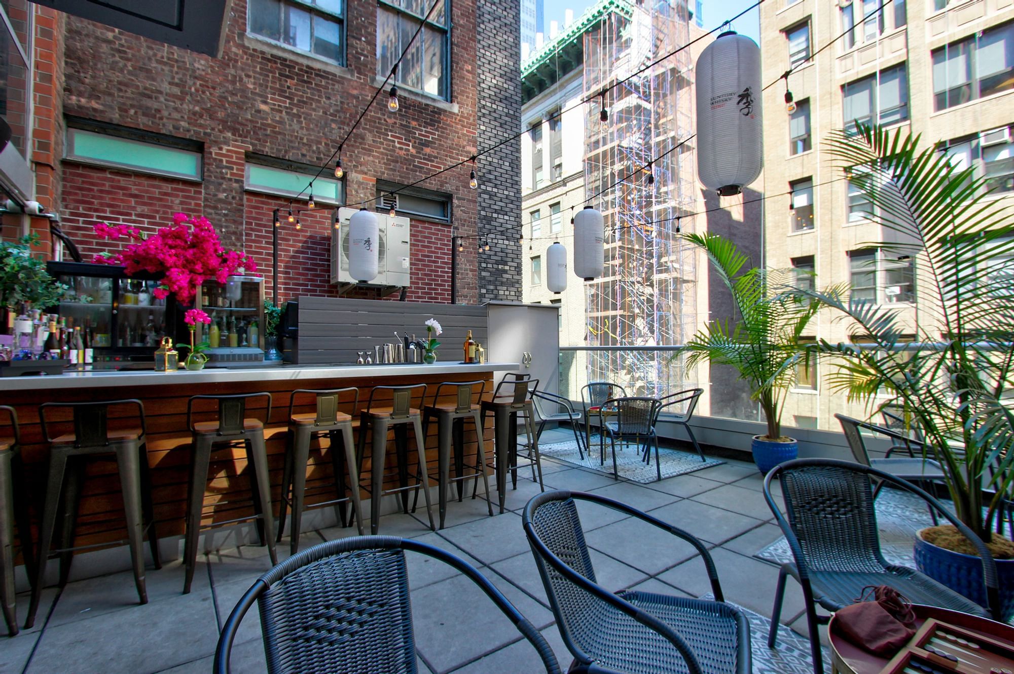 a rooftop bar with a counter and stools, and several tables and chairs