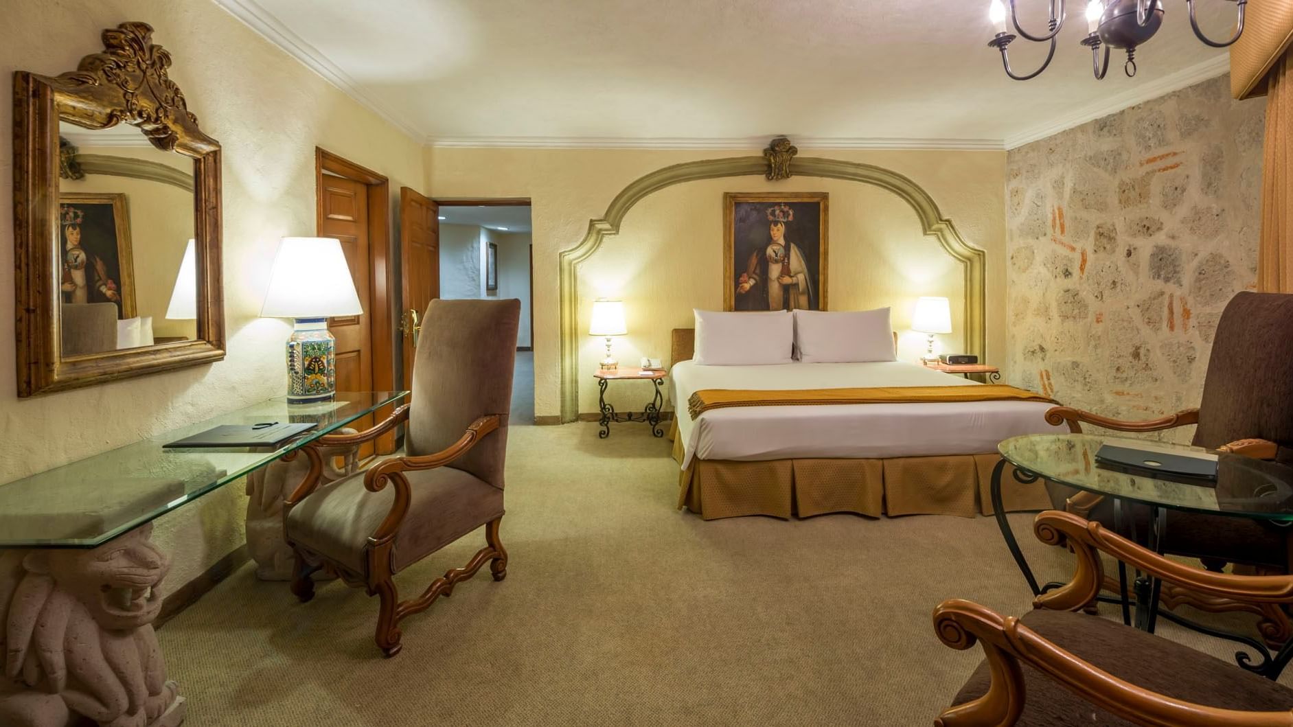 King Aguascalientes Suite with a carved headboard, portrait art, and a glass desk at Quinta Real Aguascalientes