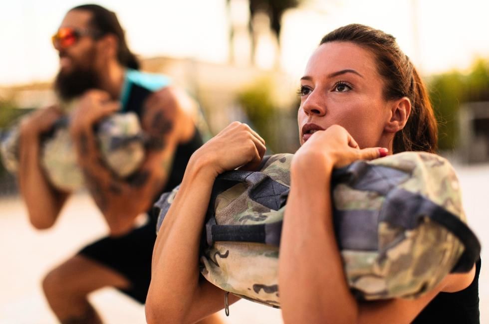 Man and women working out with sandbags a popular strongman technique 