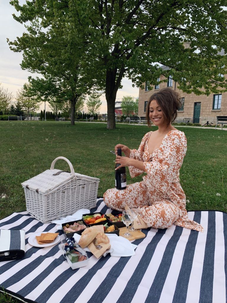Femme ouvrant une bouteille de vin lors d'un pique-nique à l'hôtel X
