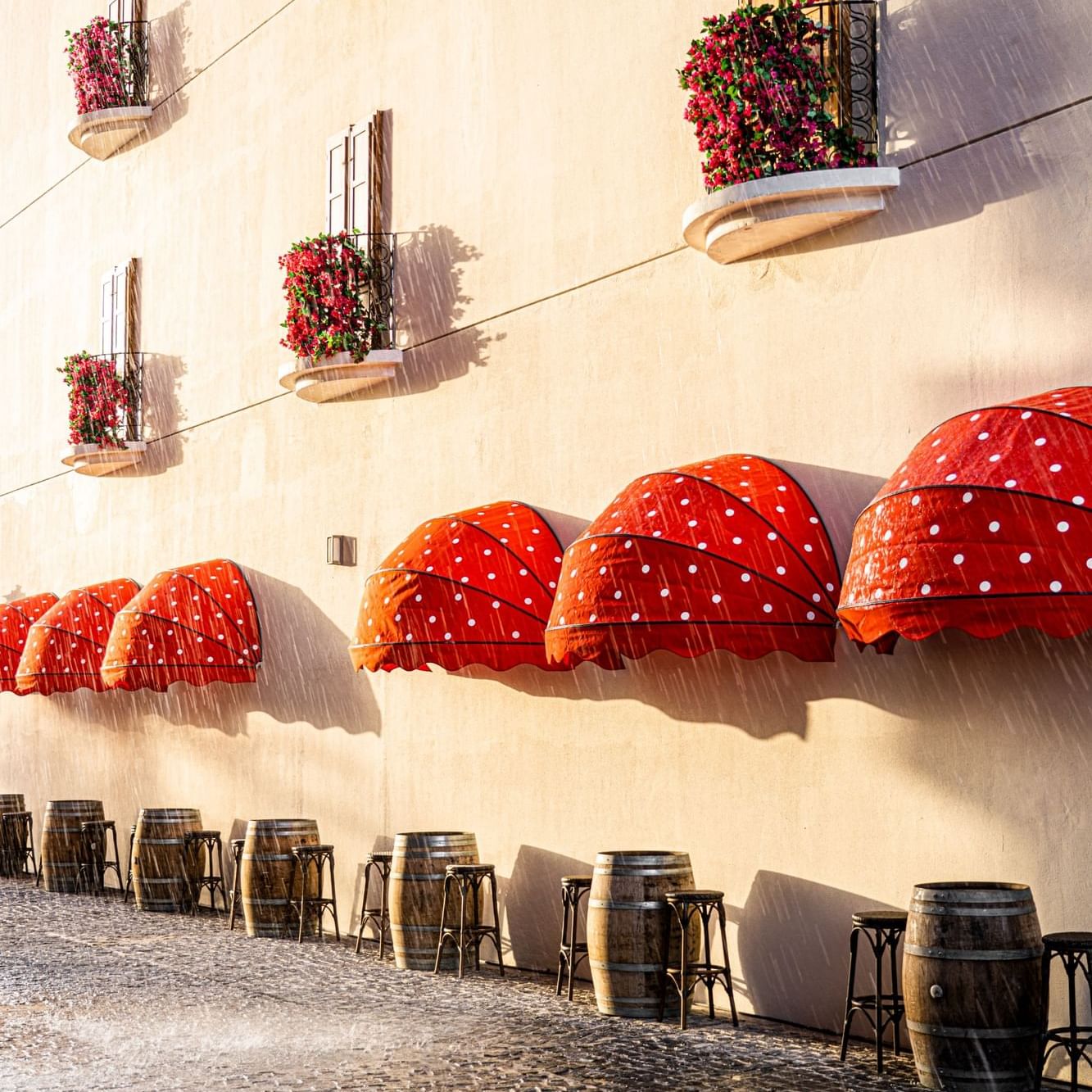 Red unlatched canopies over the Restaurant dining tables on a rainy day at Côte d'Azur Resort