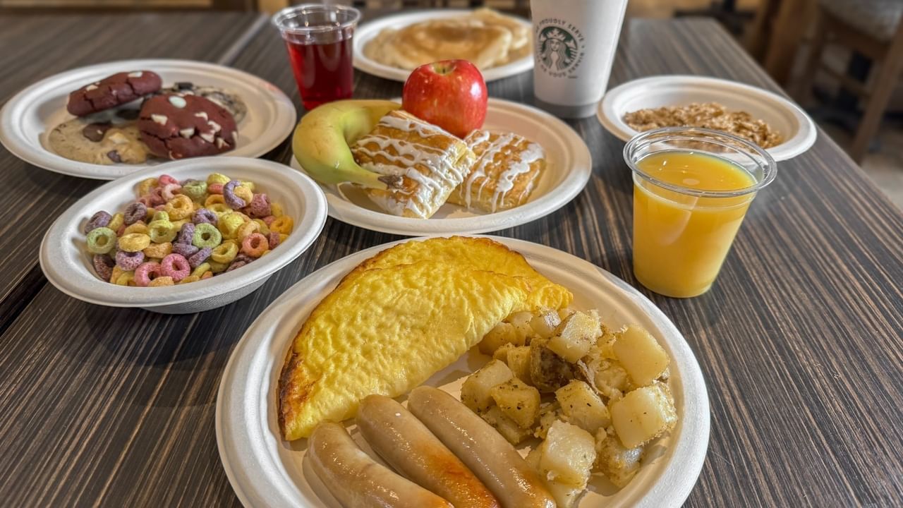 Plates of assorted breakfast foods and drinks on a table.