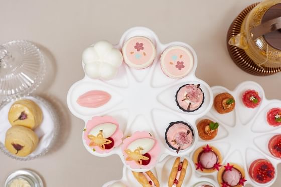 Close-up of dessert platter with a teapot in the background at The Okura Prestige Bangkok