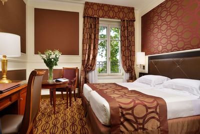 King bed, coffee table with chairs, work desk, lamp & window in Classic Twin Room at Grand Visconti Palace