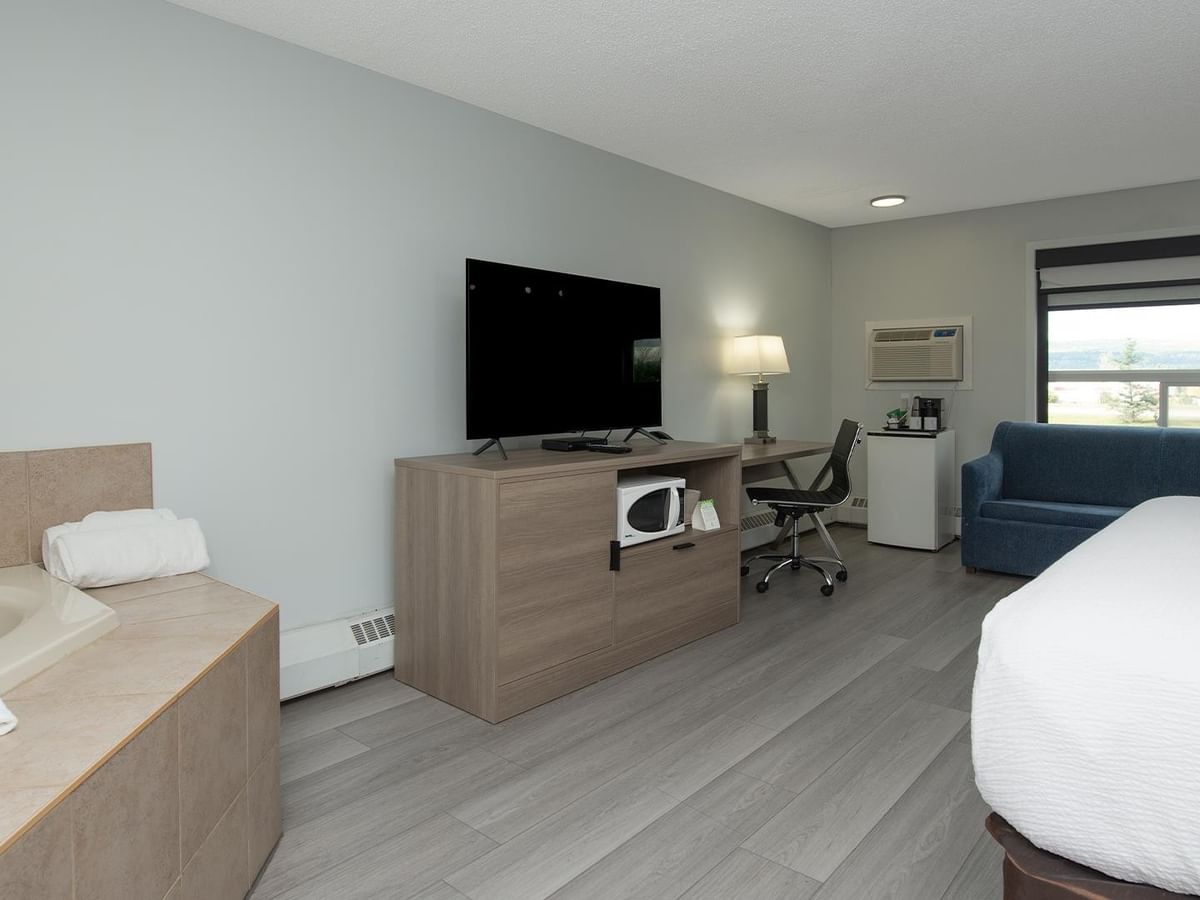 Coast Premium King Suite with soaker tub, work desk, blue sofa and flat-screen.
