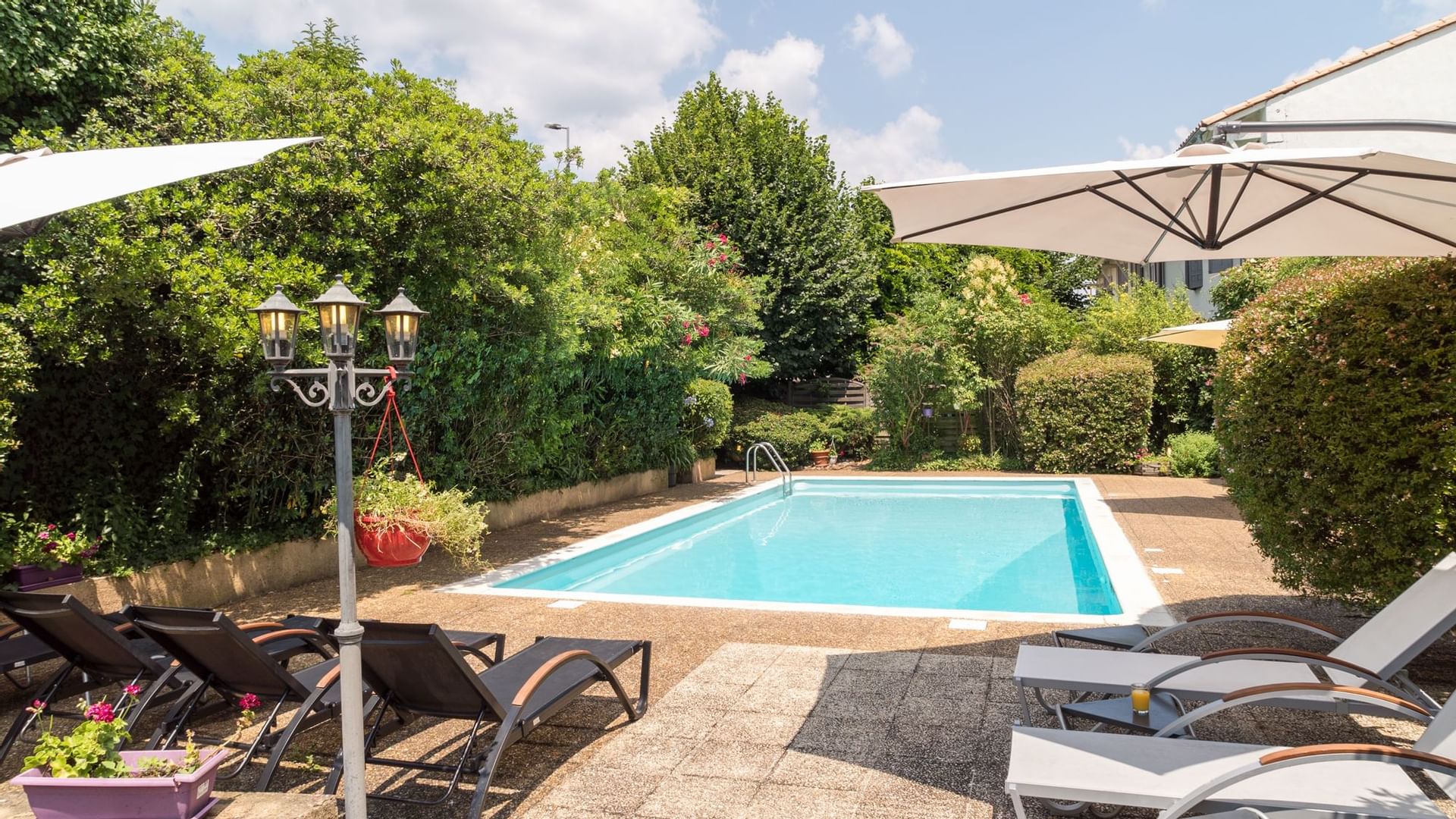 View of an outdoor pool with sunbed area at Originals Hotels