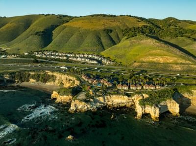 Aerial view of hotel and Pismo Preserve with green hills