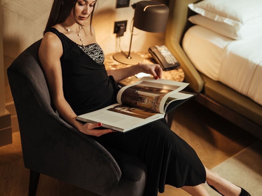 Lady reading a magazine on an armchair inside a room at Margutta 19