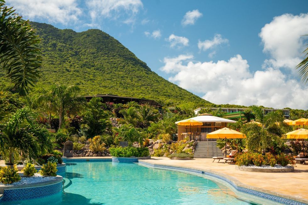 Buitenzwembad met gele parasols, omringd door groen en uitzicht op de bergen bij Golden Rock Resort