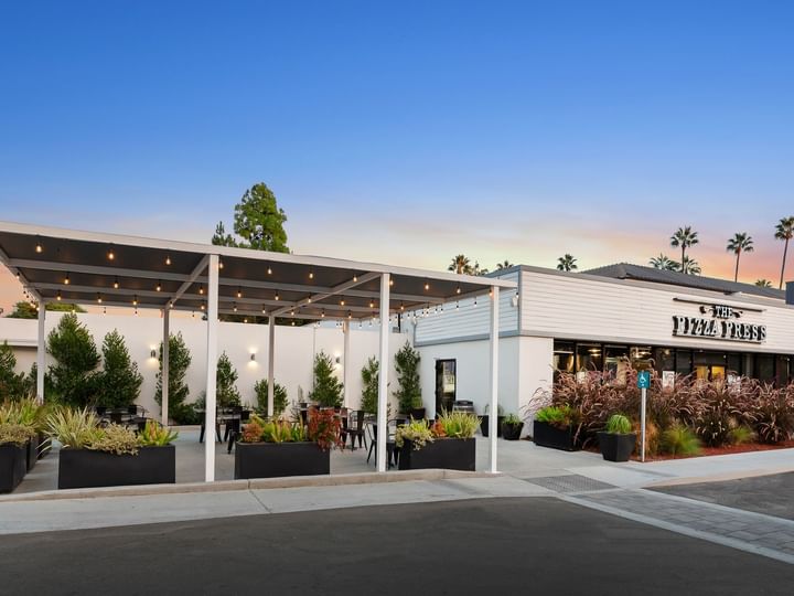 A white building with outdoor seating and a pergola