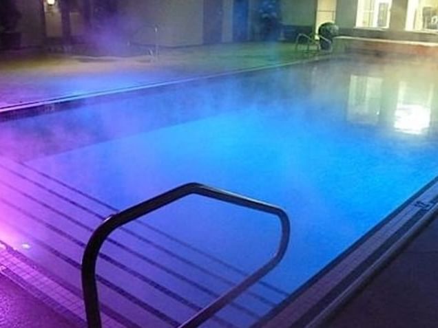 Pool & Hot Tub with lights at night in Carriage House Hotel