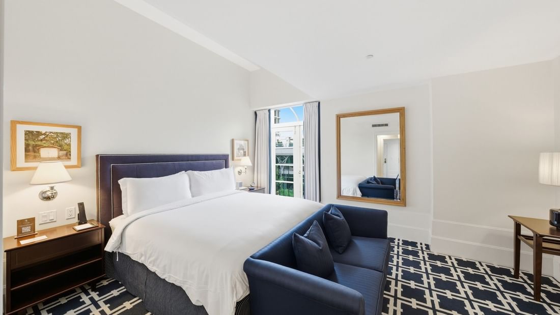 Grand Deluxe Suite with king bed, navy sofa, patterned carpet, and natural light at el PRADO Hotel, Palo Alto