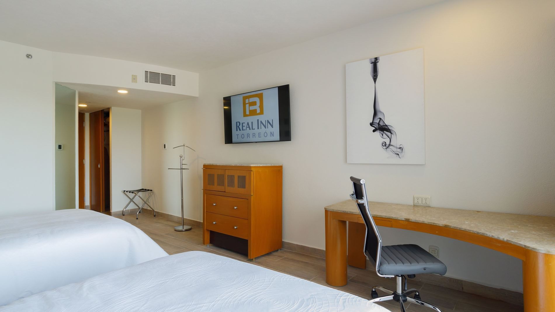 Modern 2 Double Deluxe room featuring a marble-top desk, branded TV, and minimalist wall art at Real Inn Torreon