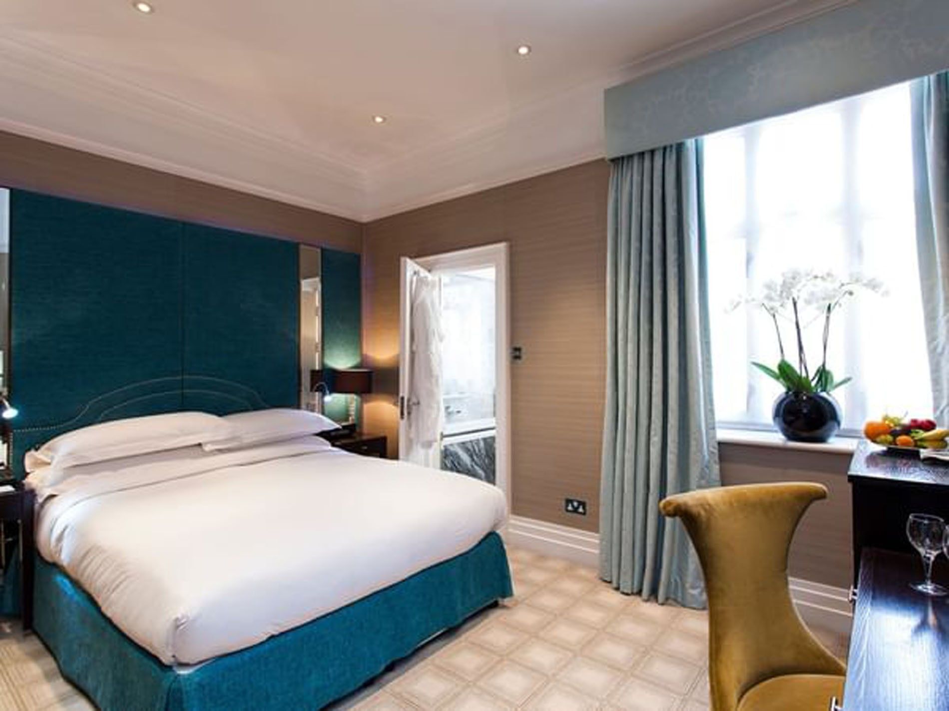 Bed with side tables and a working desk near a window in Classic double room at The Capital Hotel, Apartments and Townhouse