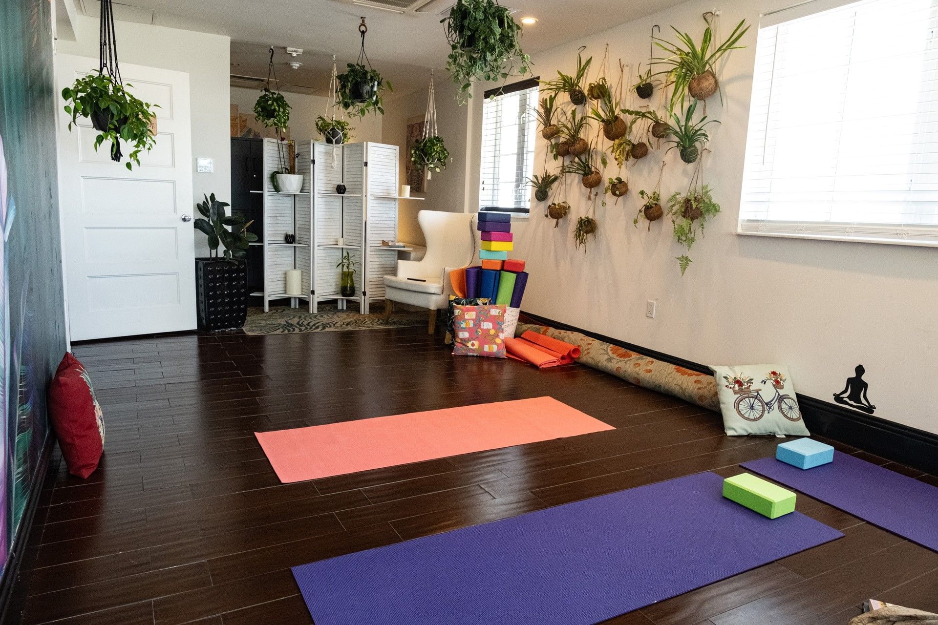 a yoga room with mats, blocks, and plants