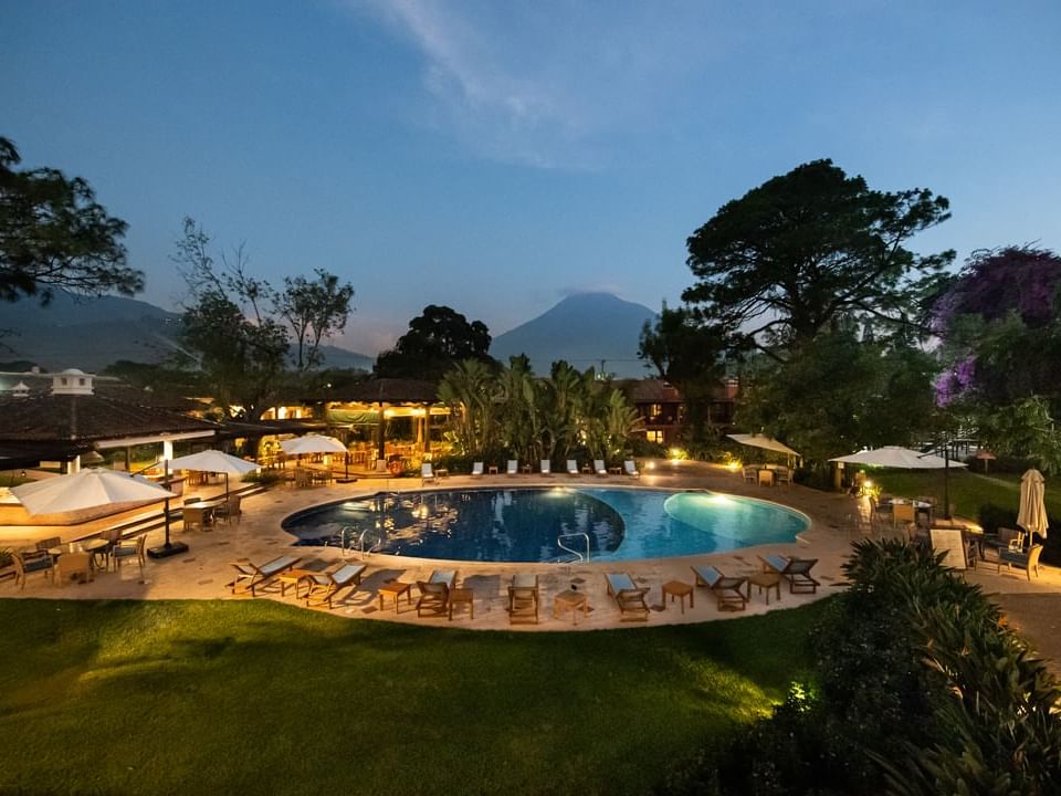 Outdoor pool with sun loungers surrounded by lush greenery at Porta Hotel Antigua