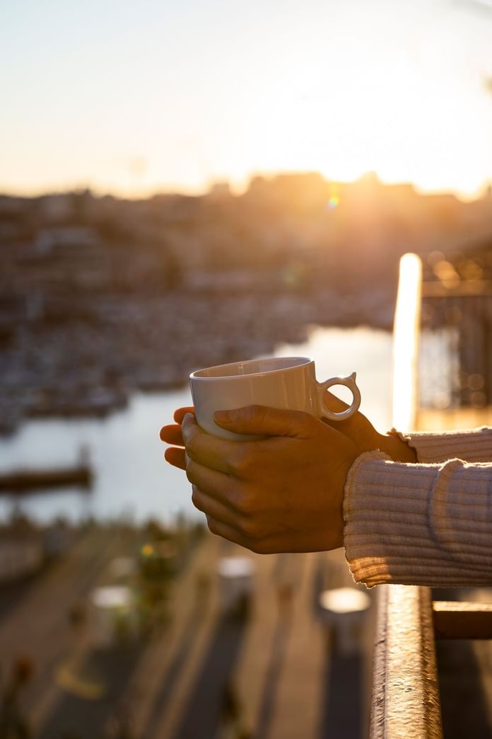 Close-up of a person holding a mug outside the balcony at Oceania Hotels