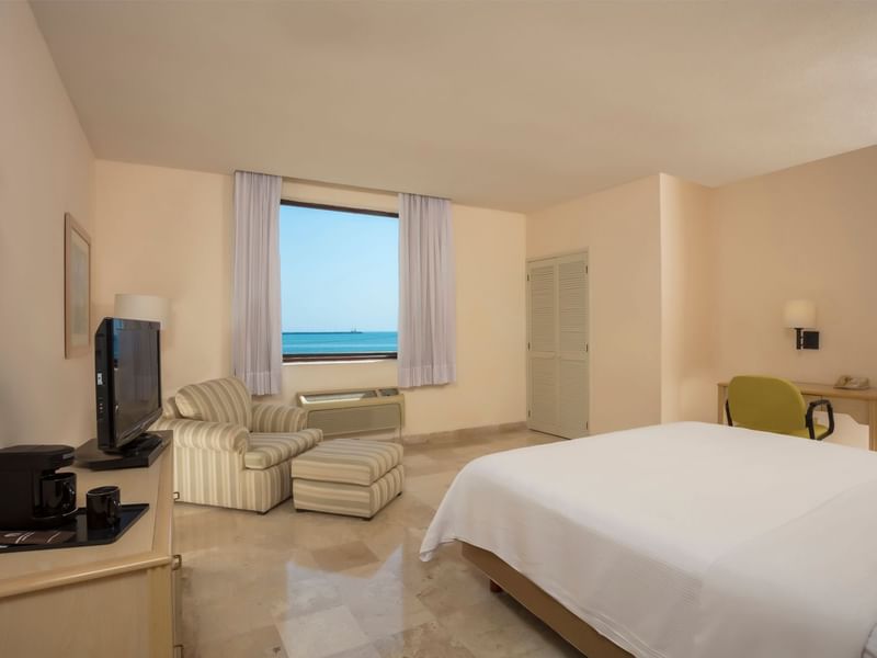 King-sized bed with a TV and a Chair in Executive Room at Fiesta Inn