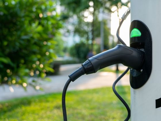 Close-up of an electric vehicle charging connector plugged into a charging station at Hotel des Innovations