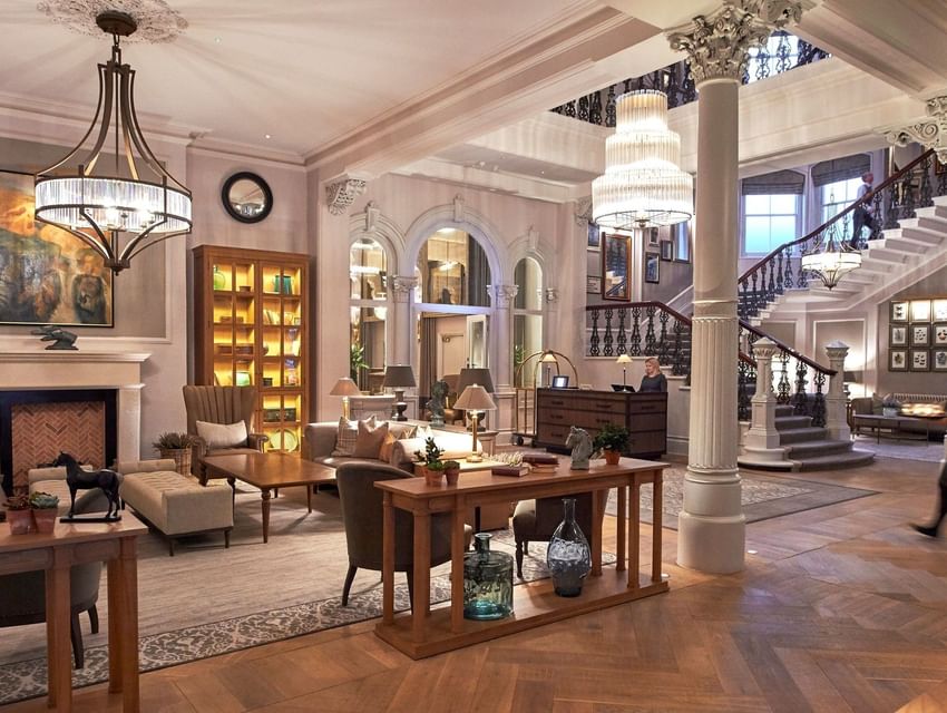 Modern lobby with a beautiful herringbone floor a grand staircase and chandeliers defines the luxury of The Milner York