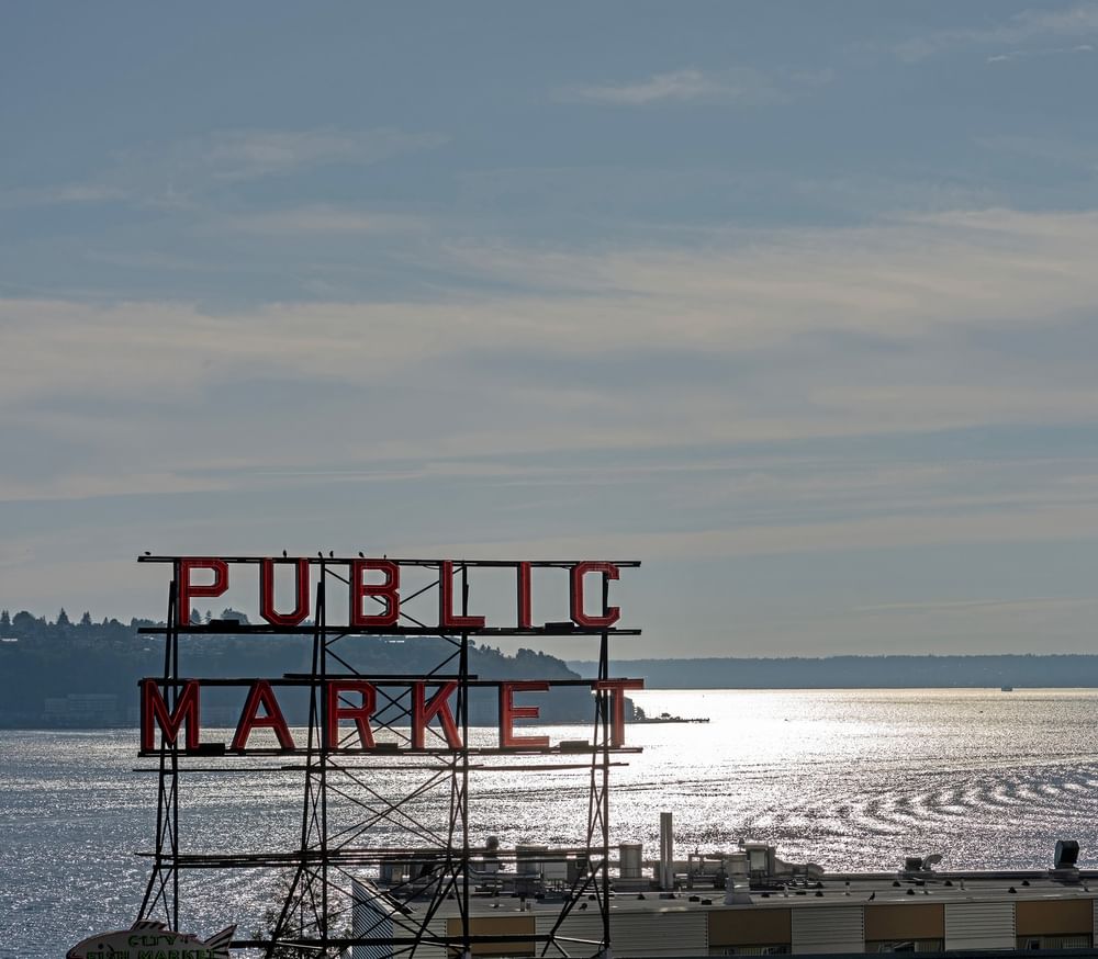 View of Public Market sign over water with a ferry in the distance near Warwick Seattle