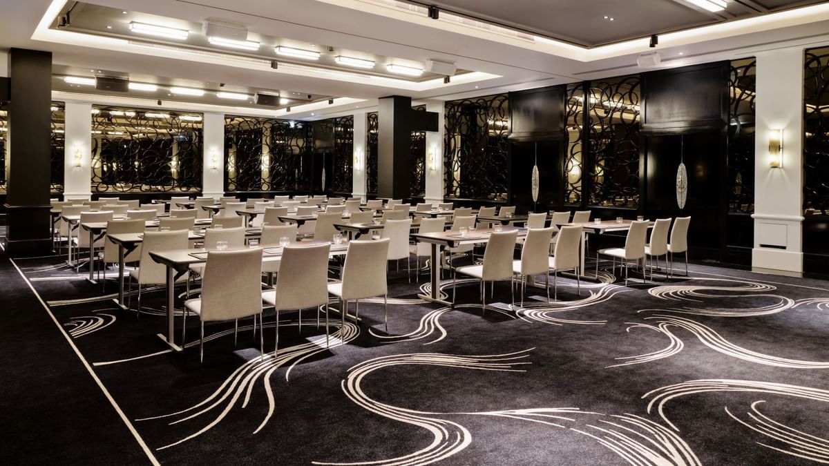 Classroom set-up with patterned carpet and dark wood paneling in the Danziger Suite at The May Fair Hotel