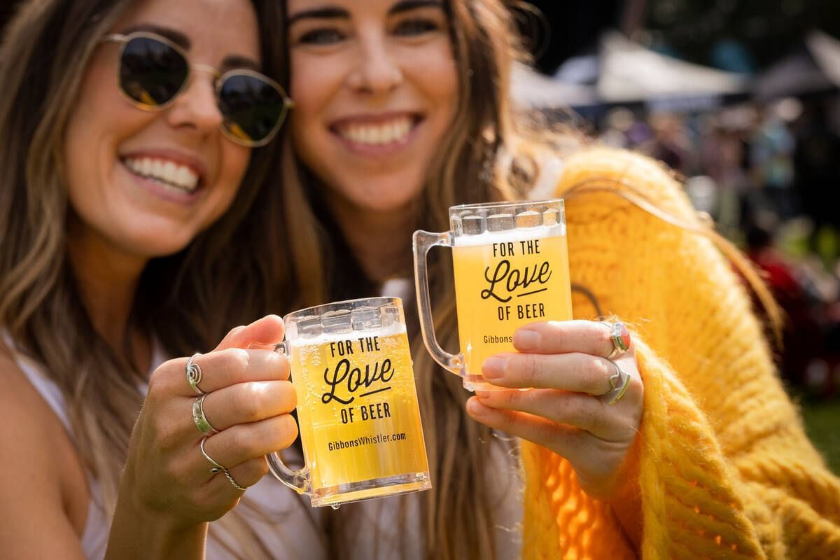 Two women holding beer glasses in The Whistler Village Beer Festival near Blackcomb Springs Suites