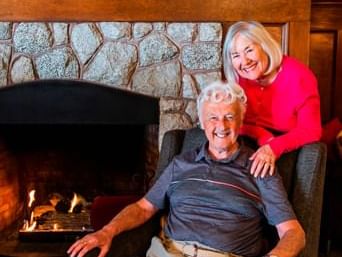 An elderly couple posing for a picture by the fireplace at Pendray Inn & Tea House