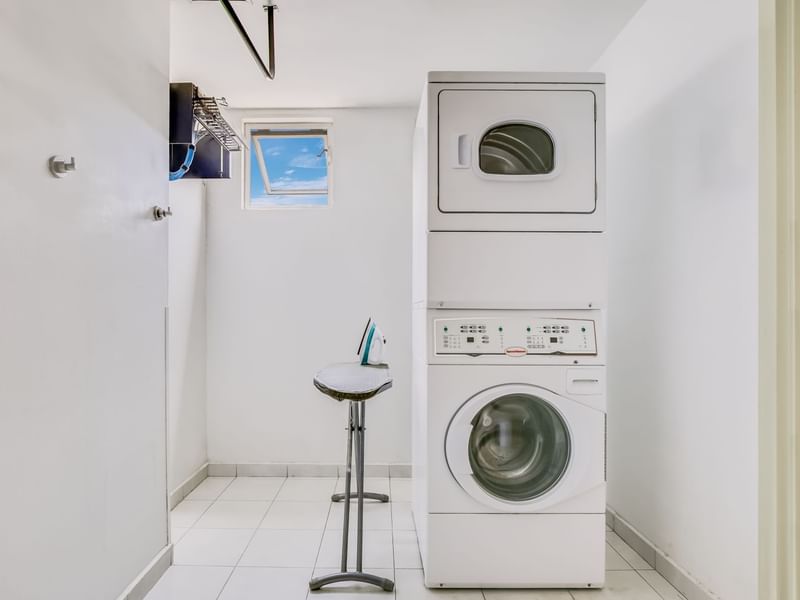 Laundry room with white walls & a washing machine at One Hotels
