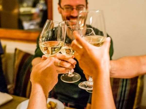 Friends enjoying a wine toast celebrating with glasses of white wine in a warm setting at NOI Casa Atacama