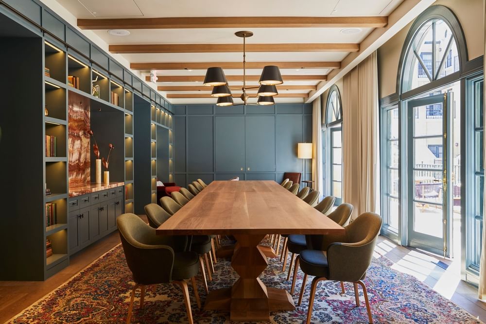 Boardroom with a long wooden table, comfortable chairs, and an elegant built-in shelving unit at El Prado Hotel