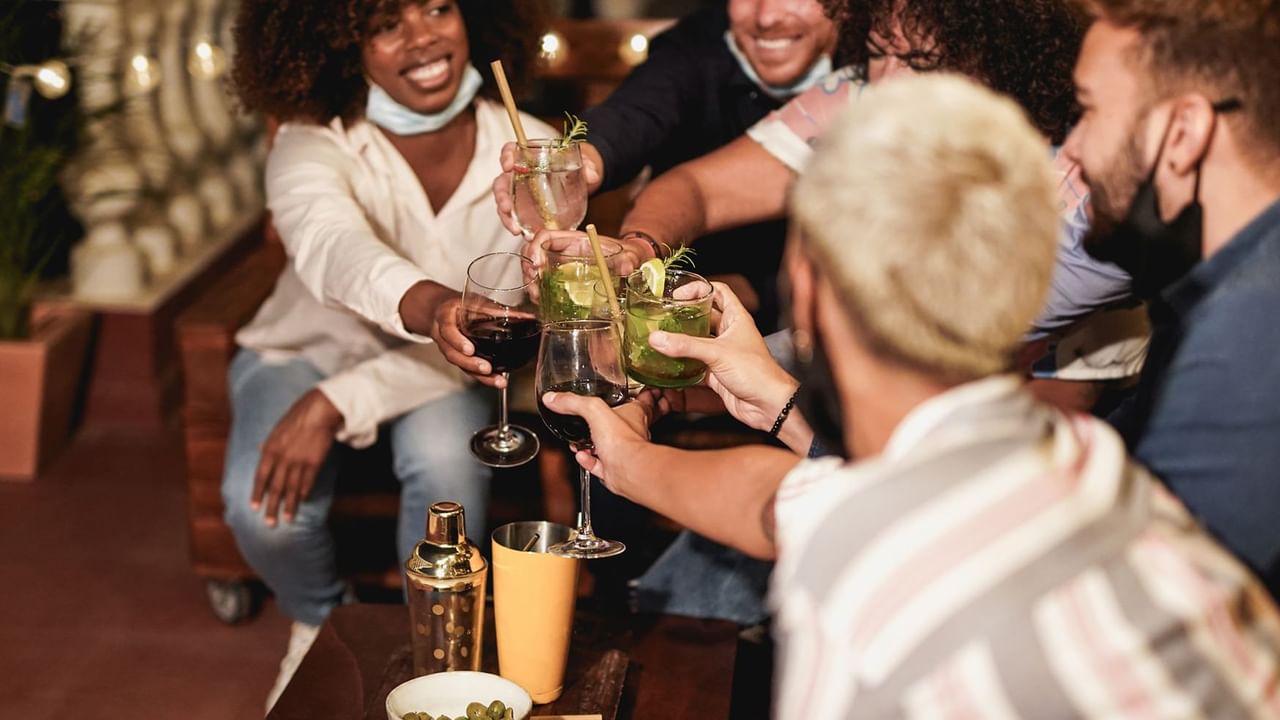 People celebrating and cheering with cocktails in Sluice Box Lounge near Midnight Sun, a Coast Hotel