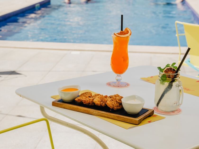 Poolside table with Crispy chicken wings and dipping sauces with two mojitos at The Magnolia Hotel