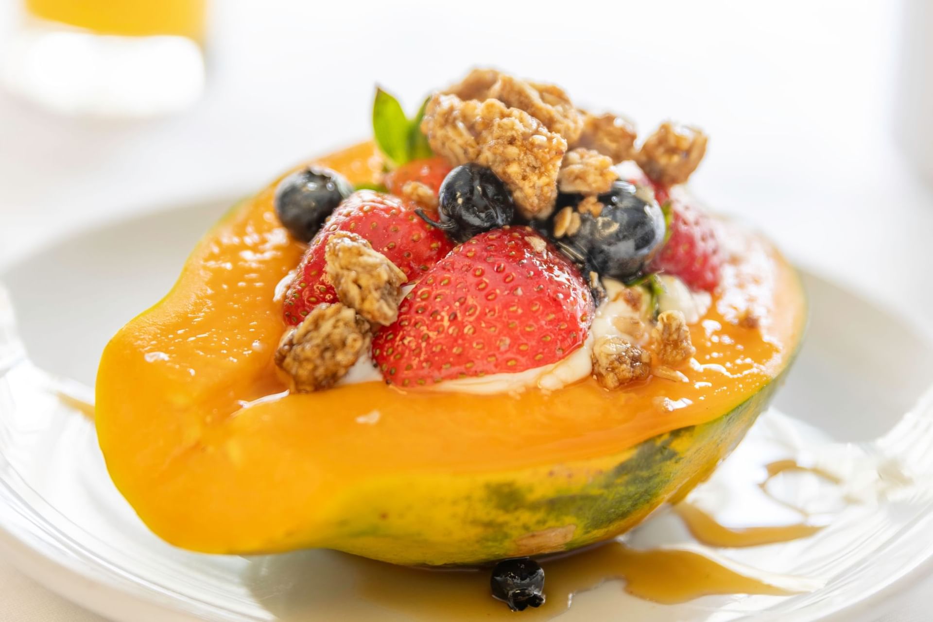 a papaya half filled with yogurt, fruit, and granola