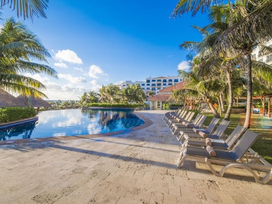 Outdoor Pool area with a row of sunbeds at Gamma Hotels