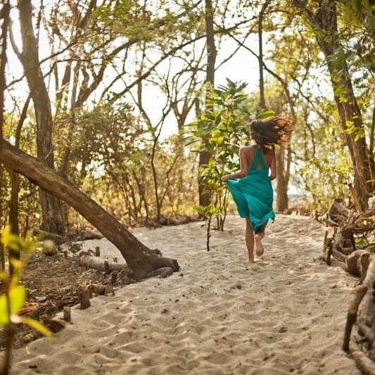 A Lady running on a trail of sand near Cala Luna Hotel