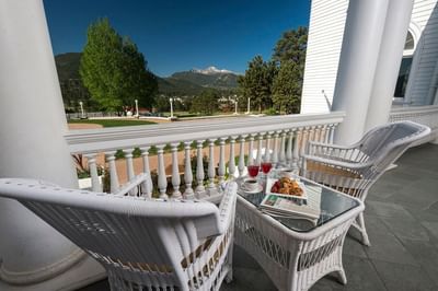 A tranquil balcony at The Stanley Hotel with two wicker chairs and a table set for morning tea overlooking the mountains