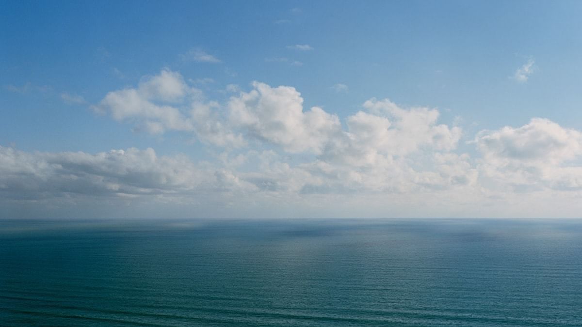 Calm blue sea under a sky with fluffy white clouds near Crown Hotels