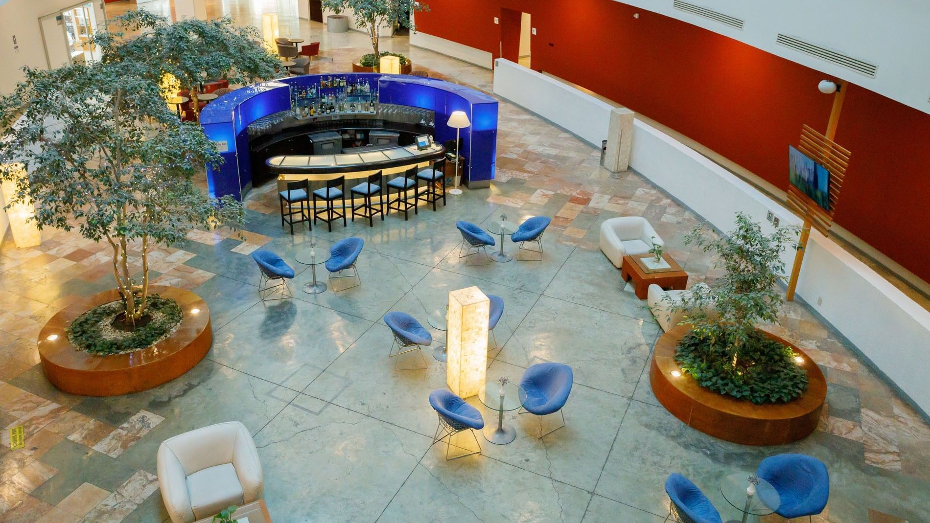 Aerial view of Lobby Bar with blue neon accents, trees, and stylish seating at Camino Real Pachuca