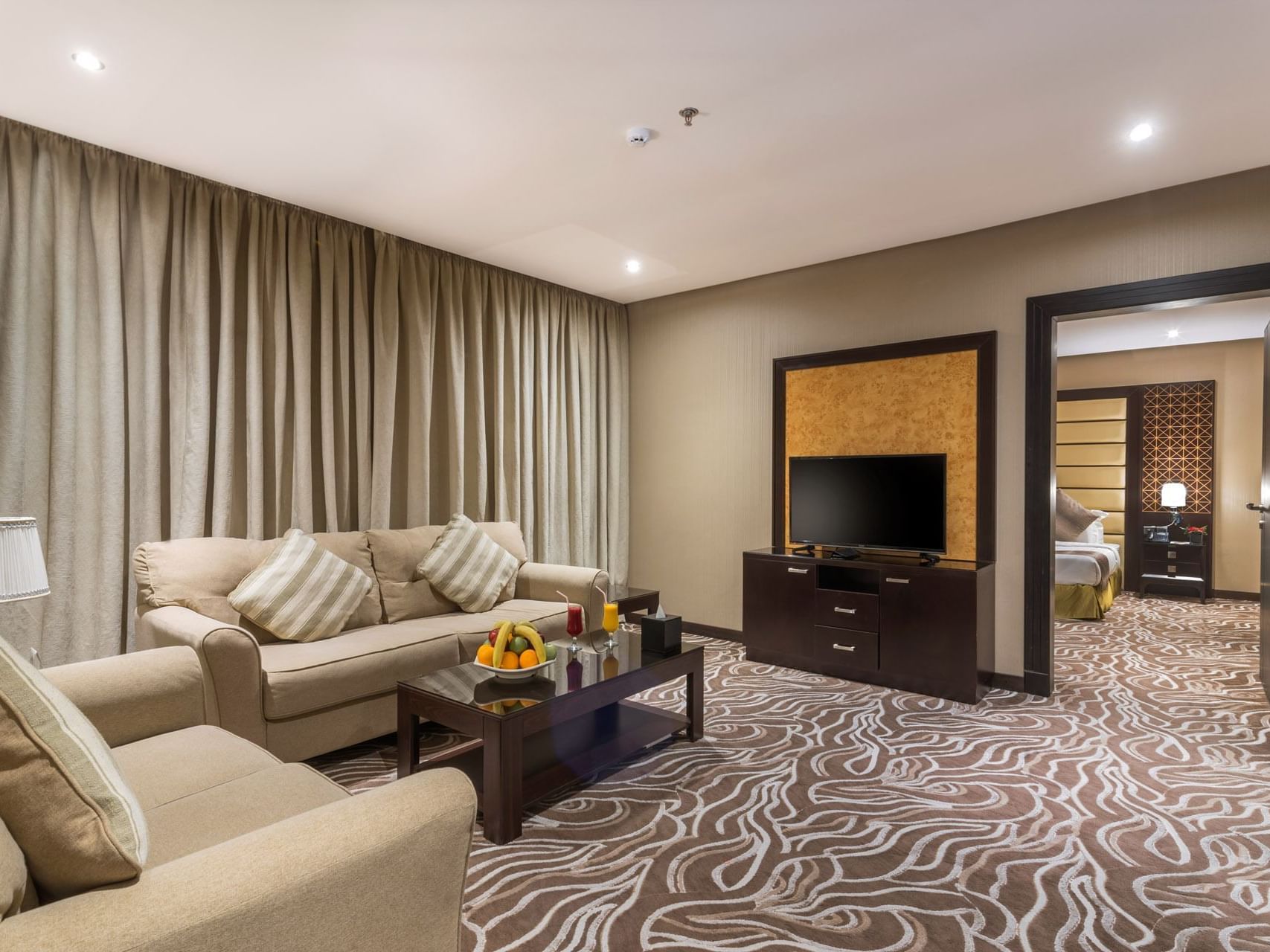 Junior Suite living area with an open door leading to the bedroom at Warwick Al Khobar