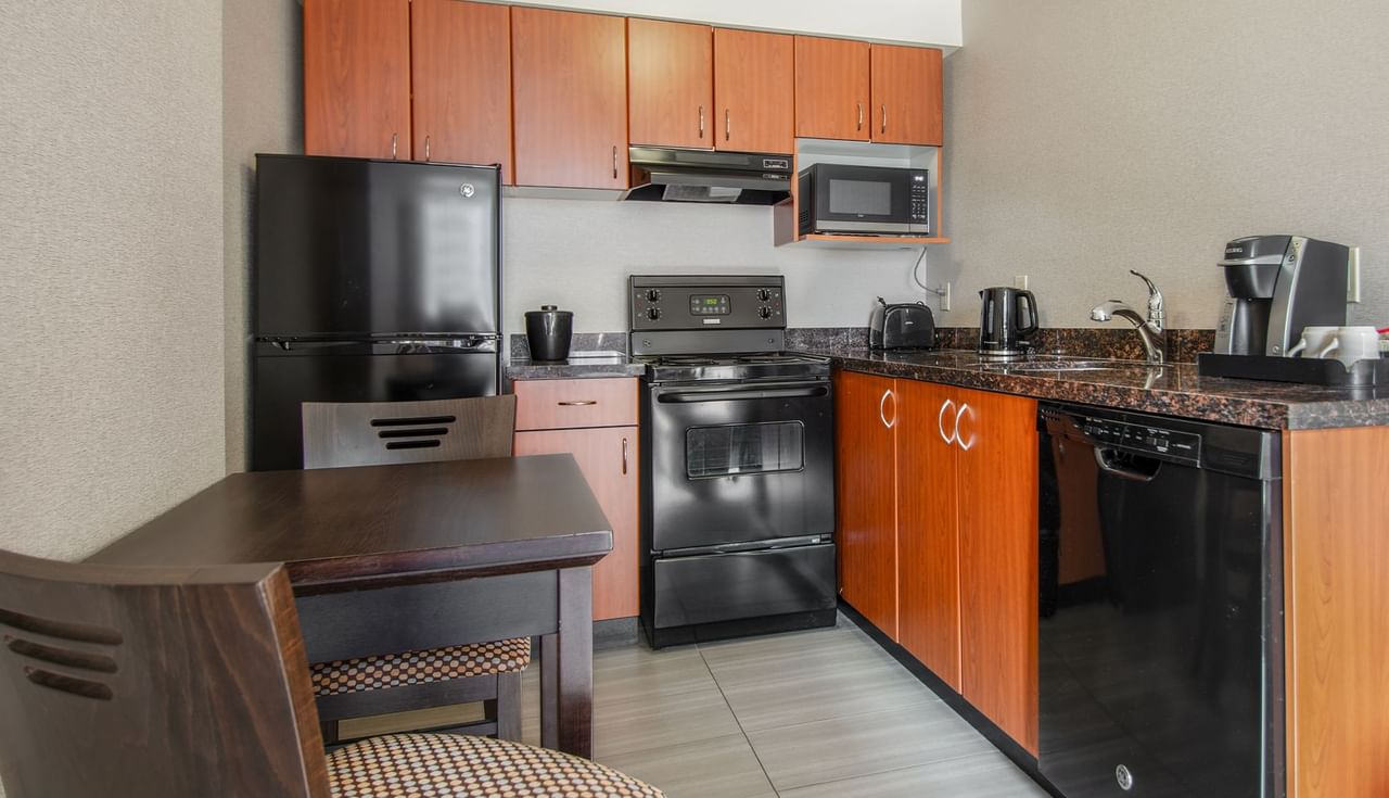 Hotel suite kitchen with oven, microwave, fridge, dining area, stove, and coffee maker