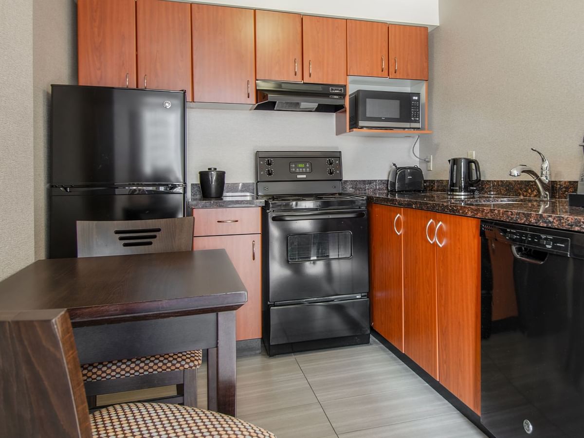 Hotel suite kitchen with oven, microwave, fridge, dining area, stove, and coffee maker