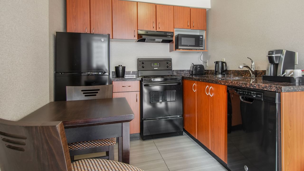 Hotel suite kitchen with oven, microwave, fridge, dining area, stove, and coffee maker
