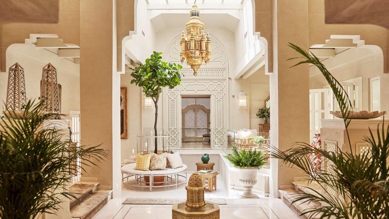 Villa del Mar lobby featuring a Moorish archway, a fountain, and a large golden chandelier at Marbella Club