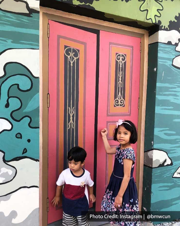 Two kids were taking a picture in front of the Kuala Kubu Bharu's street art - Lexis Suites Penang