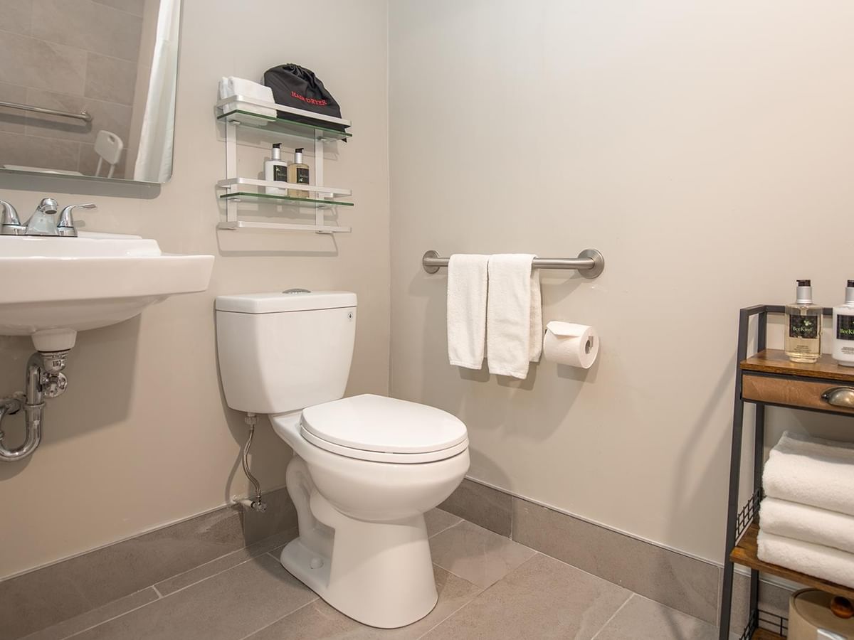 Accessible bathroom with toilet, sink, towels, and toiletries.