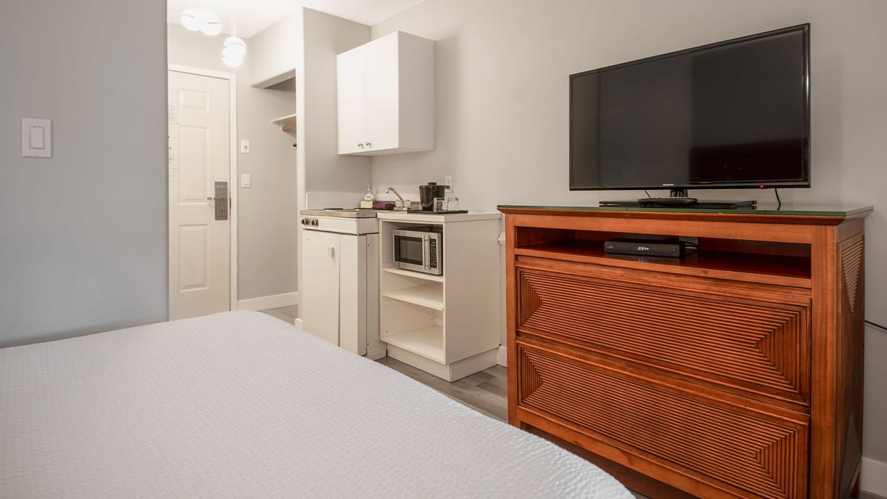 Hotel guestroom with two queen beds, TV, and a kitchenette